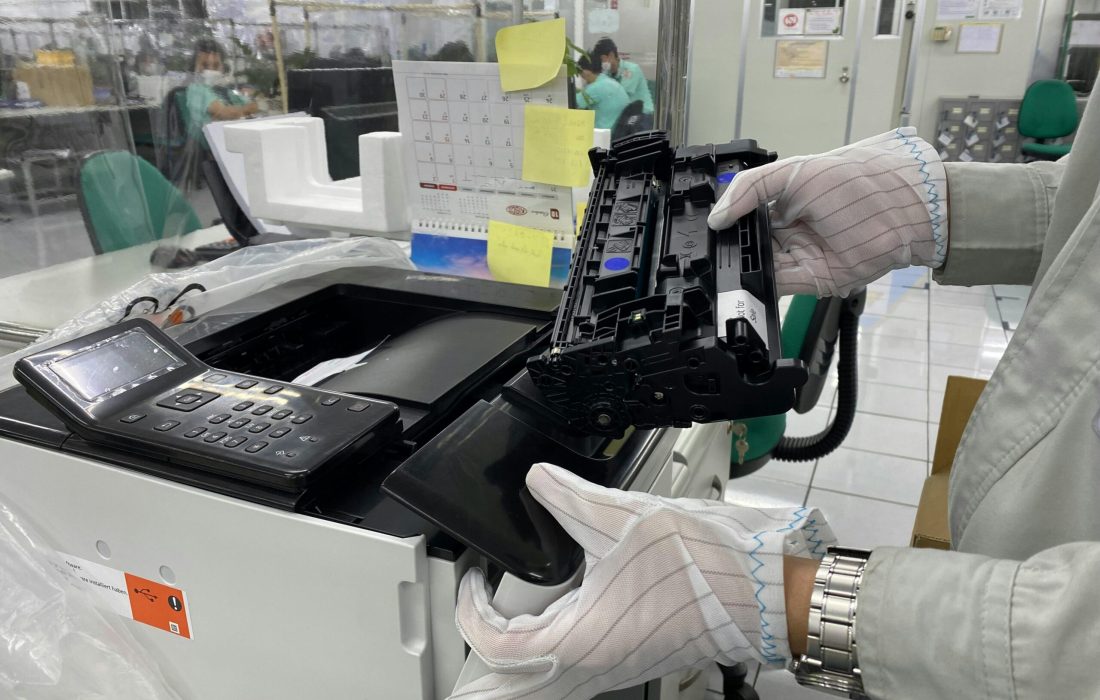 Worker replacing printer ink cartridge in a laboratory environment, highlighting technology maintenance.