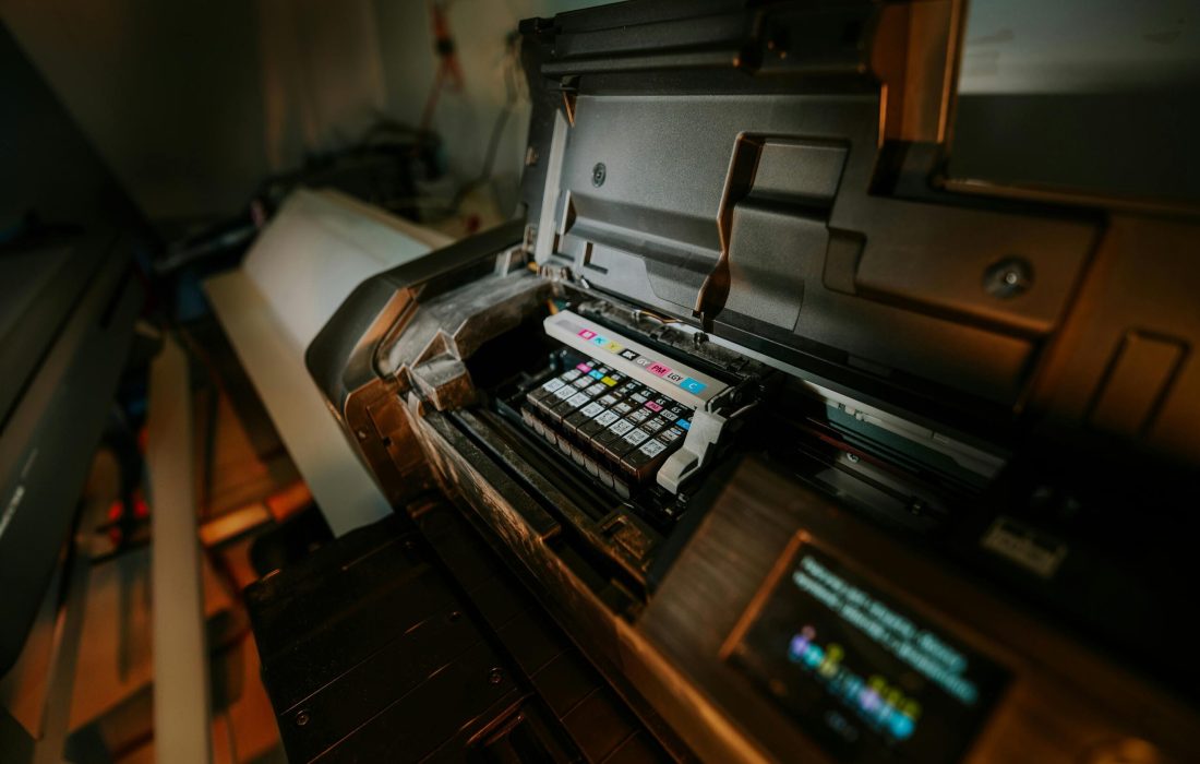 Close-up view of an inkjet printer with exposed cartridges in a workspace setting.