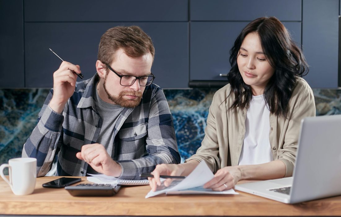 A couple is reviewing and calculating their household bills together at home.
